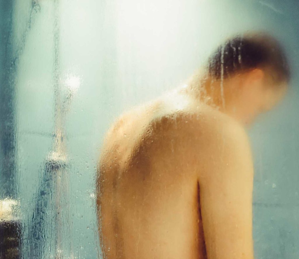 איש מתקלח מאחורי זכוכית במקלחון
